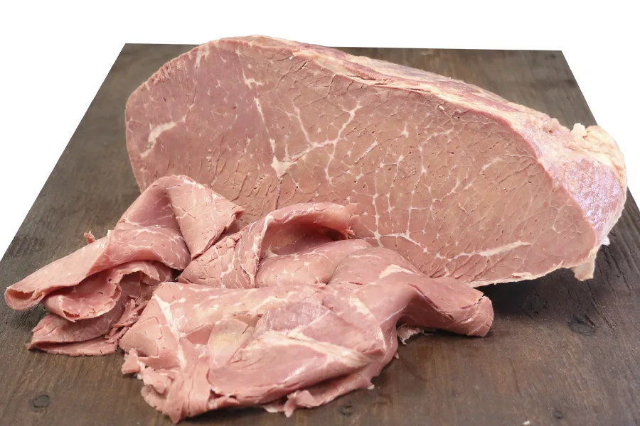 Corned beef round cut with sliced portions on slate, ideal for foodservice, wholesale distribution, and food manufacturers in B2B supply.