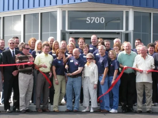 Large group of food industry professionals and executives at a ribbon-cutting ceremony outside a commercial food distribution facility building.