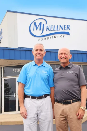 Two professional men in branded polos standing in front of Kellner Foodservice building, representing food distribution company leadership.